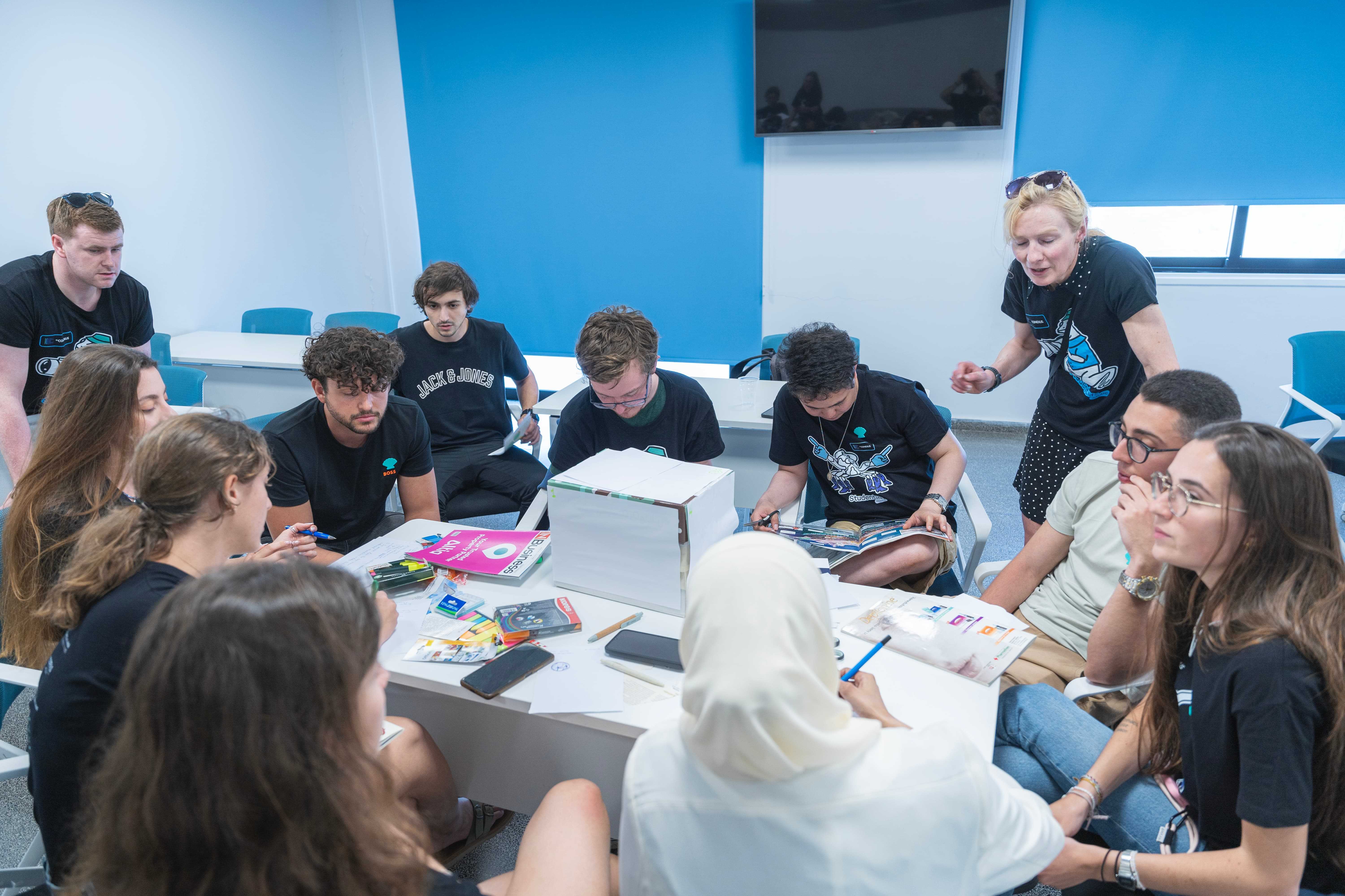 Group of students sitting around a table and working with paper to create art