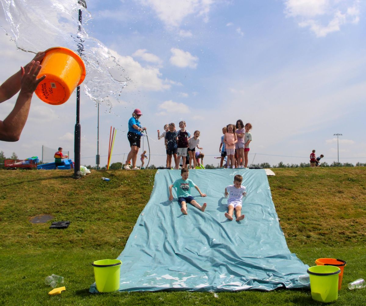 Children using water slide in the sun as part of the SETU summer activity camps.