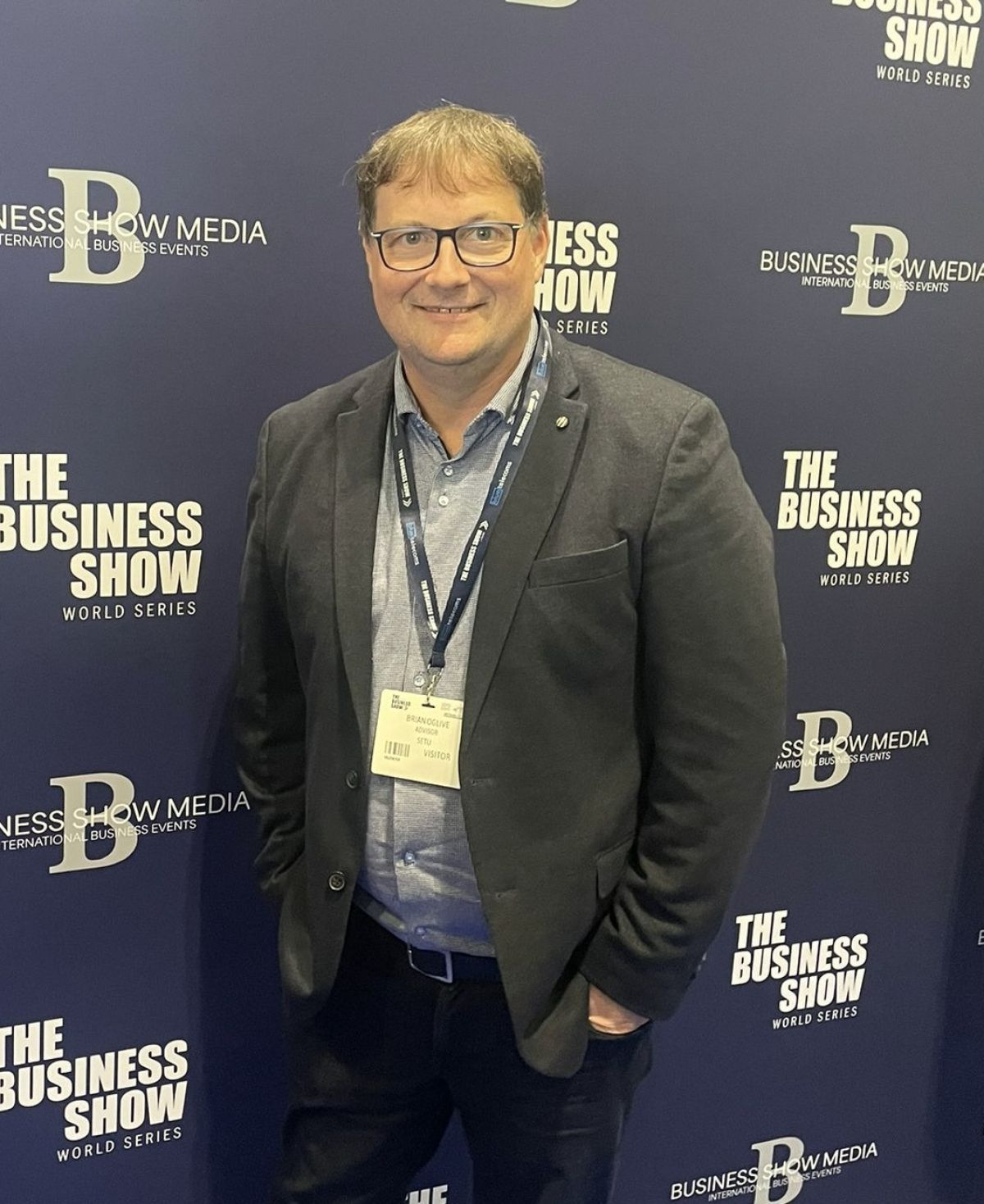 Brian Ogilvie standing in front of an event banner