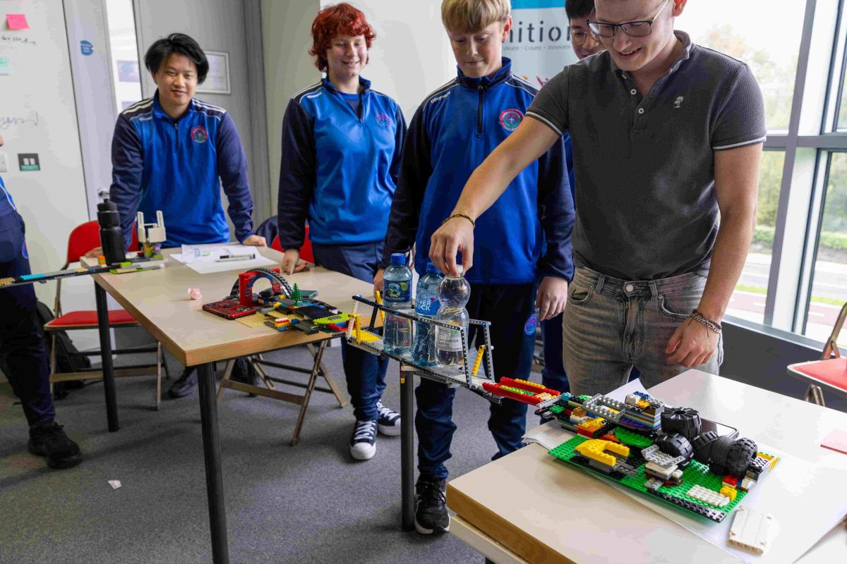 Students testing if their bridge can hold a bottle of water