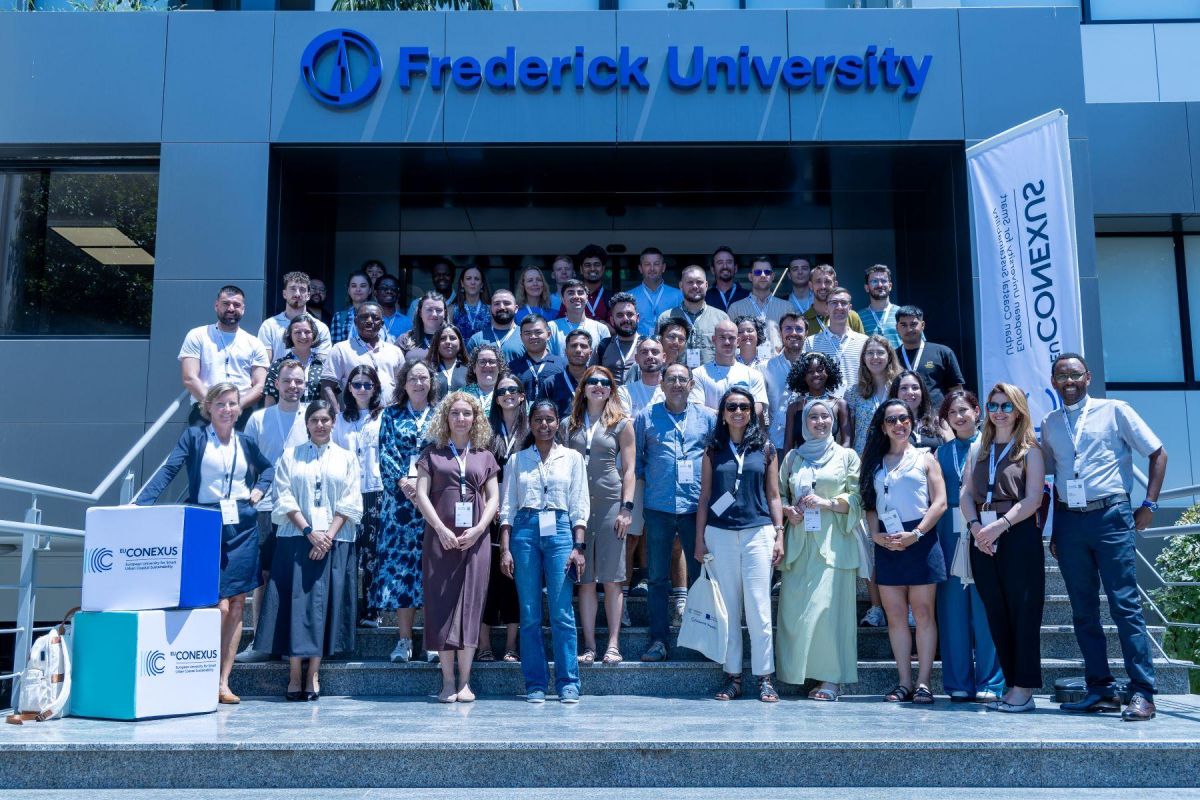 Group of staff and students standing on steps outside university