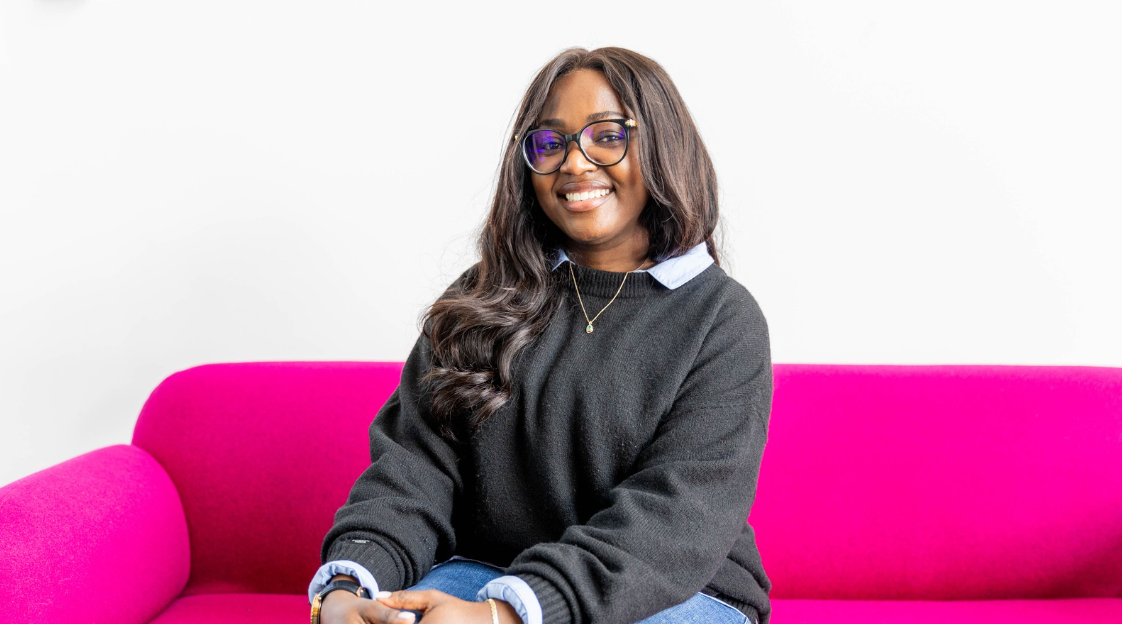 Dr Loraine Murphy sitting on bright pink sofa in front of white background