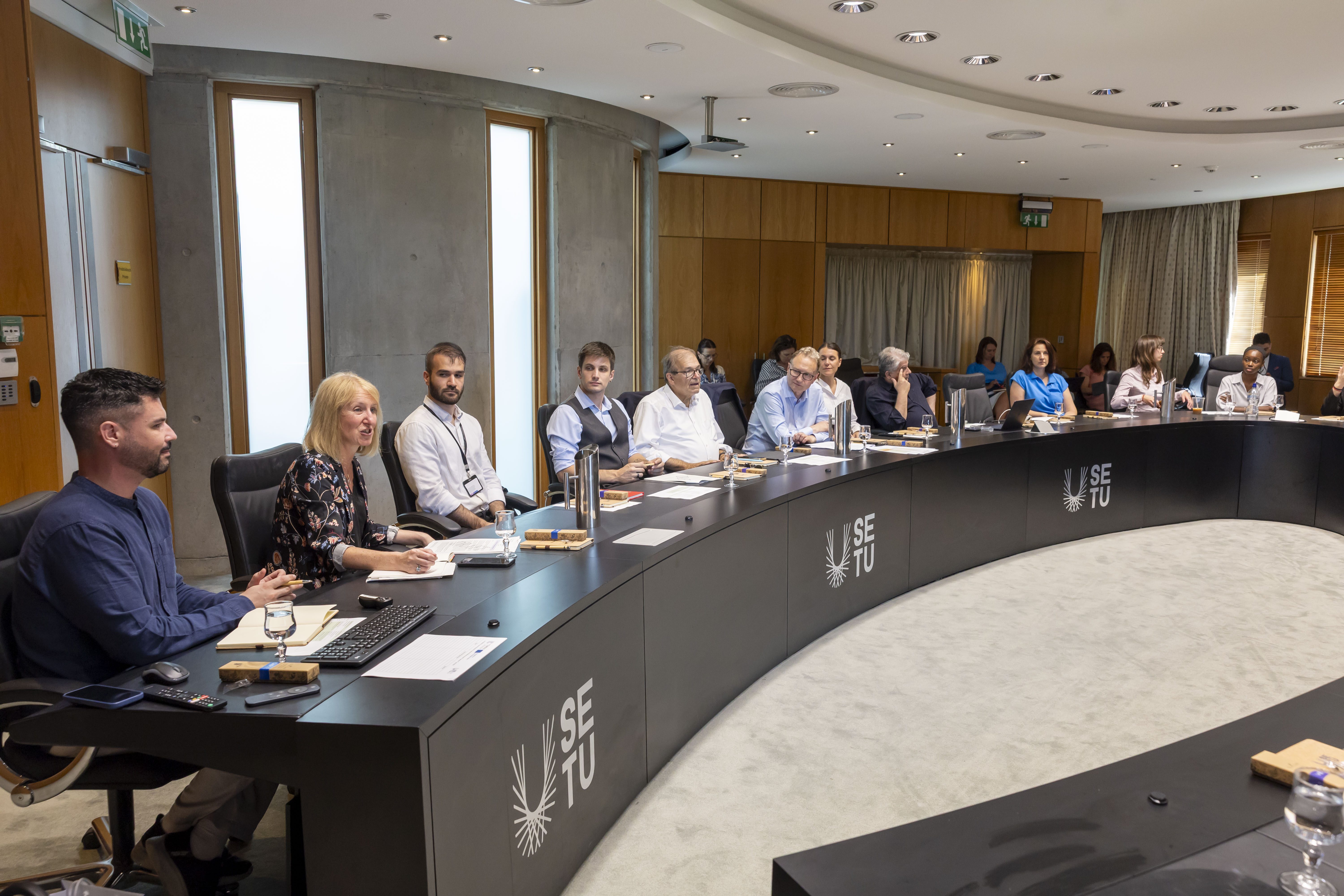 Group of people sitting around a curved table 