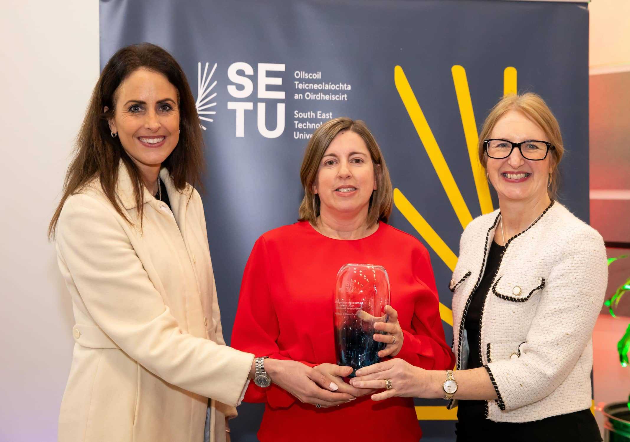Professor Gillian Gardiner, holding an award, with Professor Marie Claire on the left, and Professor Veronica Campbell on the right at the Research Excellence Awards Ceremony..