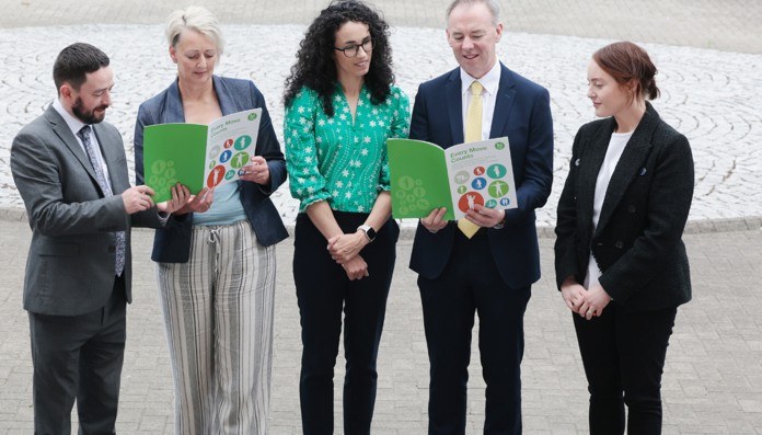 A group of professionals standing in a courtyard reading the new National Physical Activity guidelines
