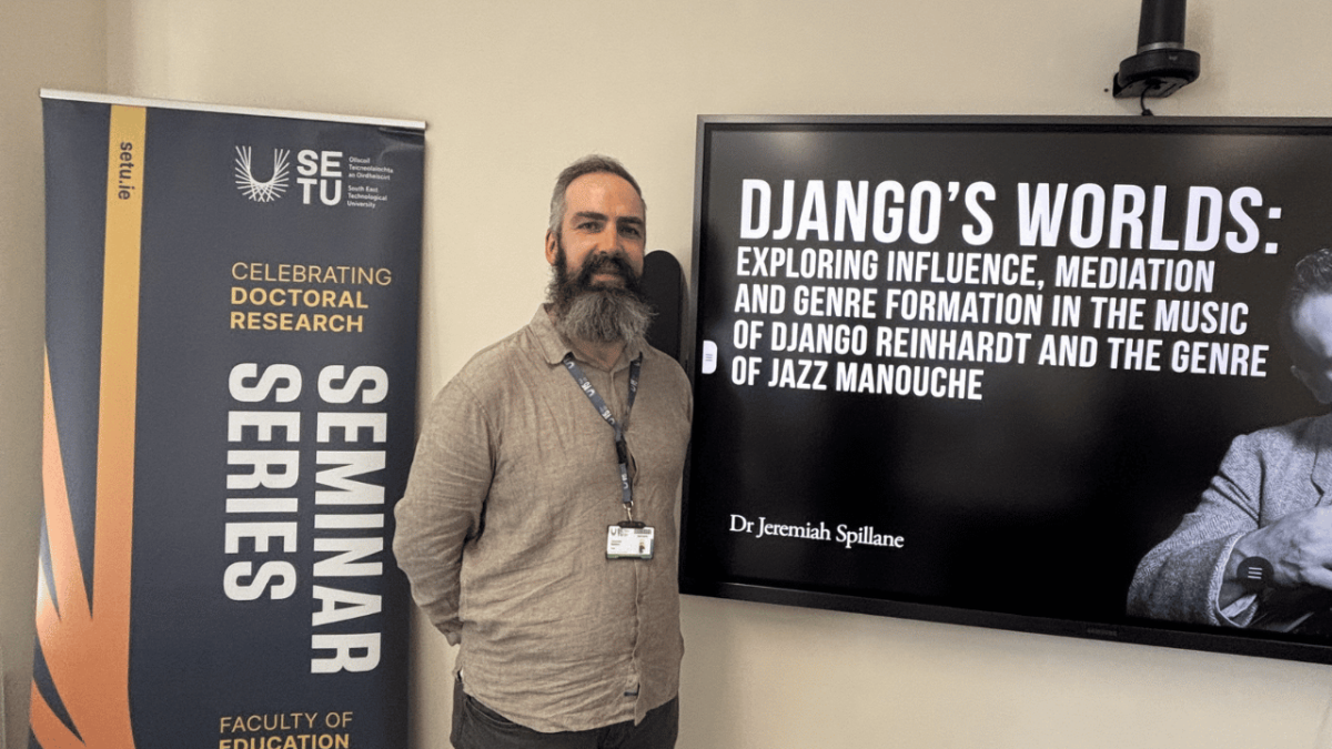 Bearded academic stands in front of screen
